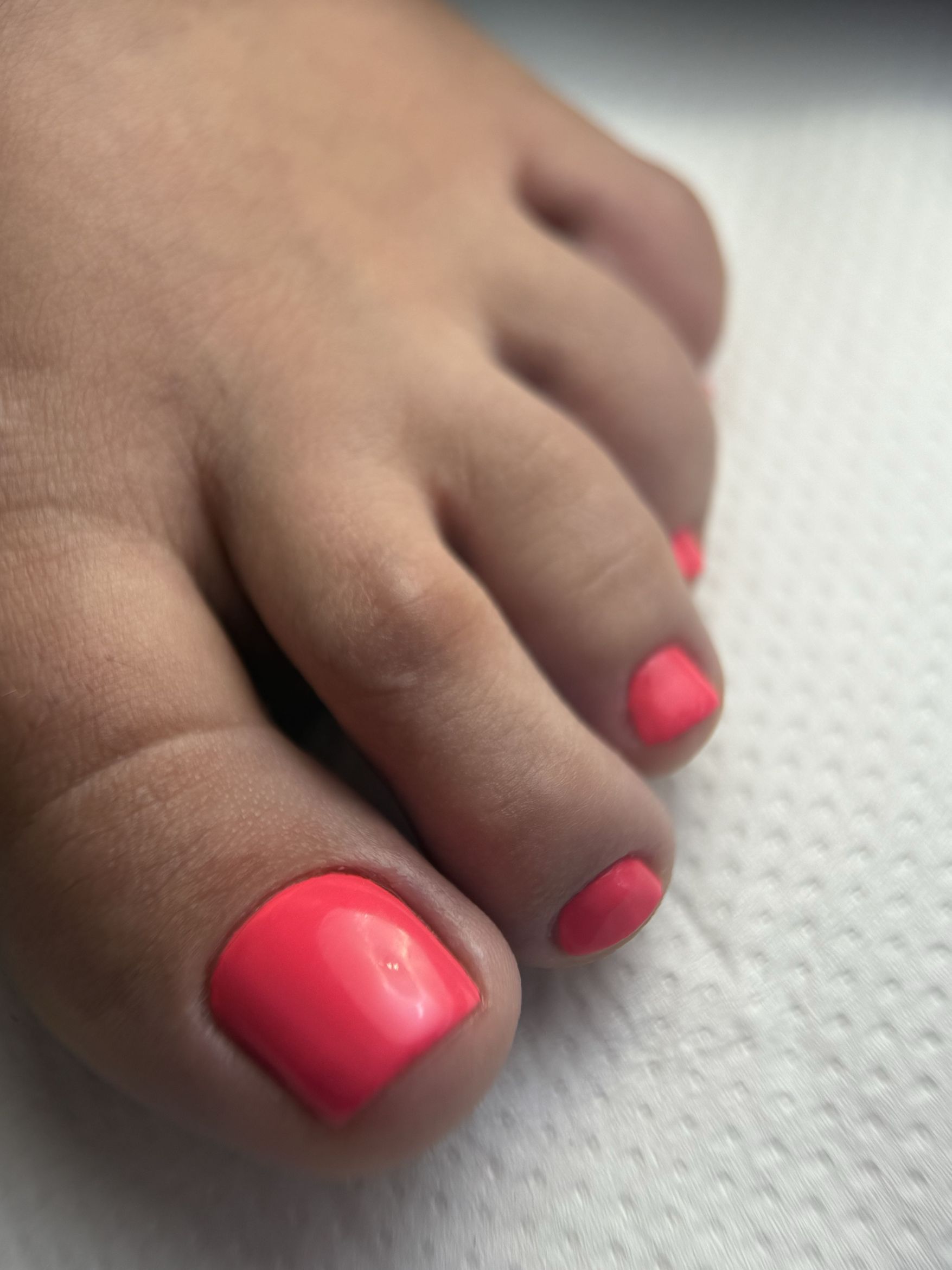 Pedicure w neonowym, koralowym kolorze, zbliżenie na palce stopy